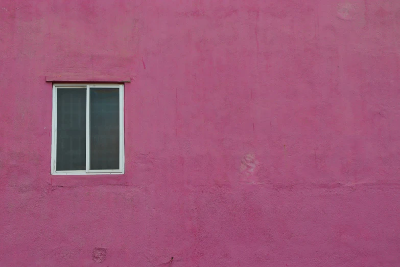 there is a window and a red building with pink paint