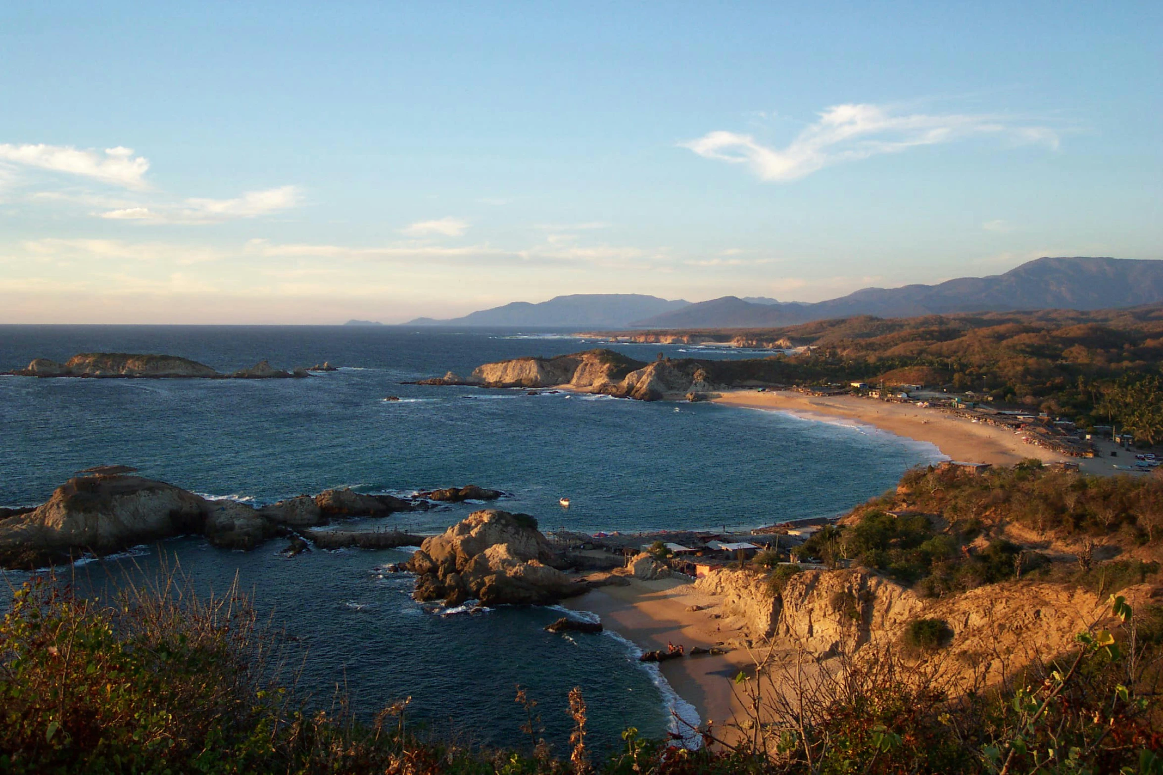 the ocean is pictured during the daytime with mountains in the distance