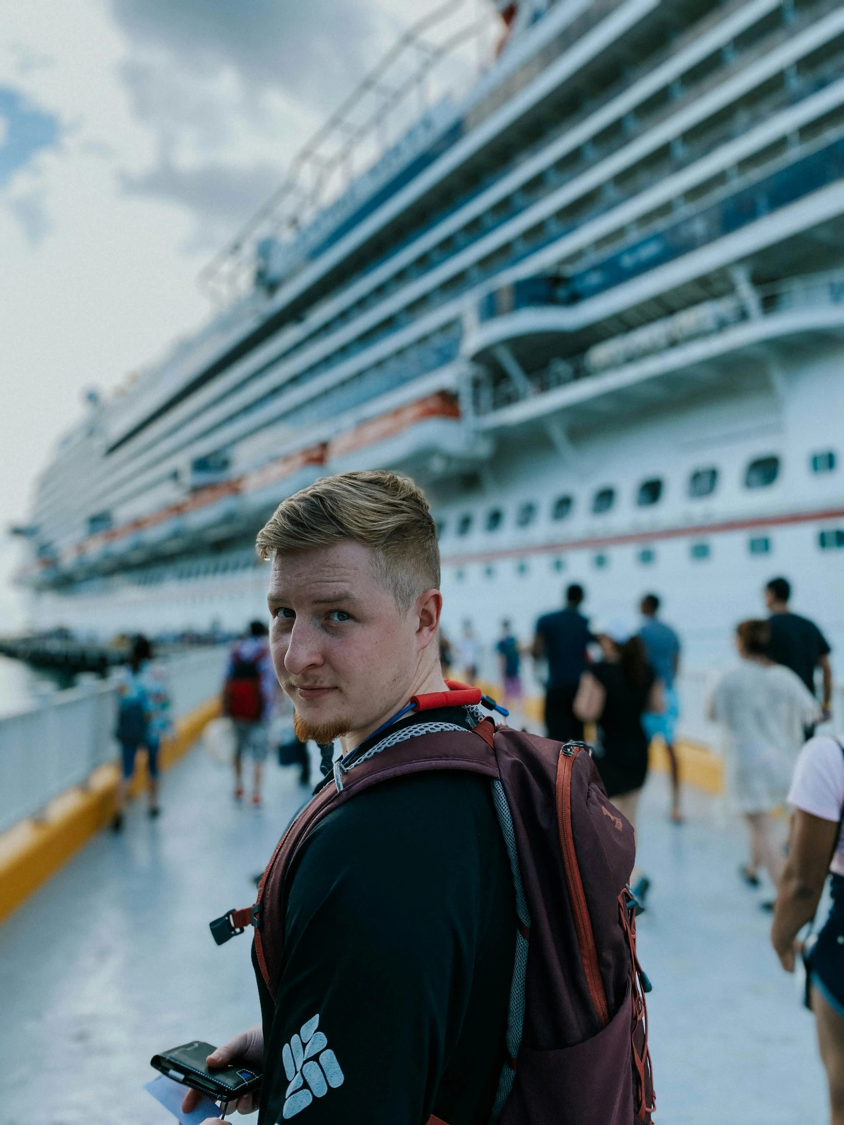 man in life vest standing on cruise liner, next to large boat