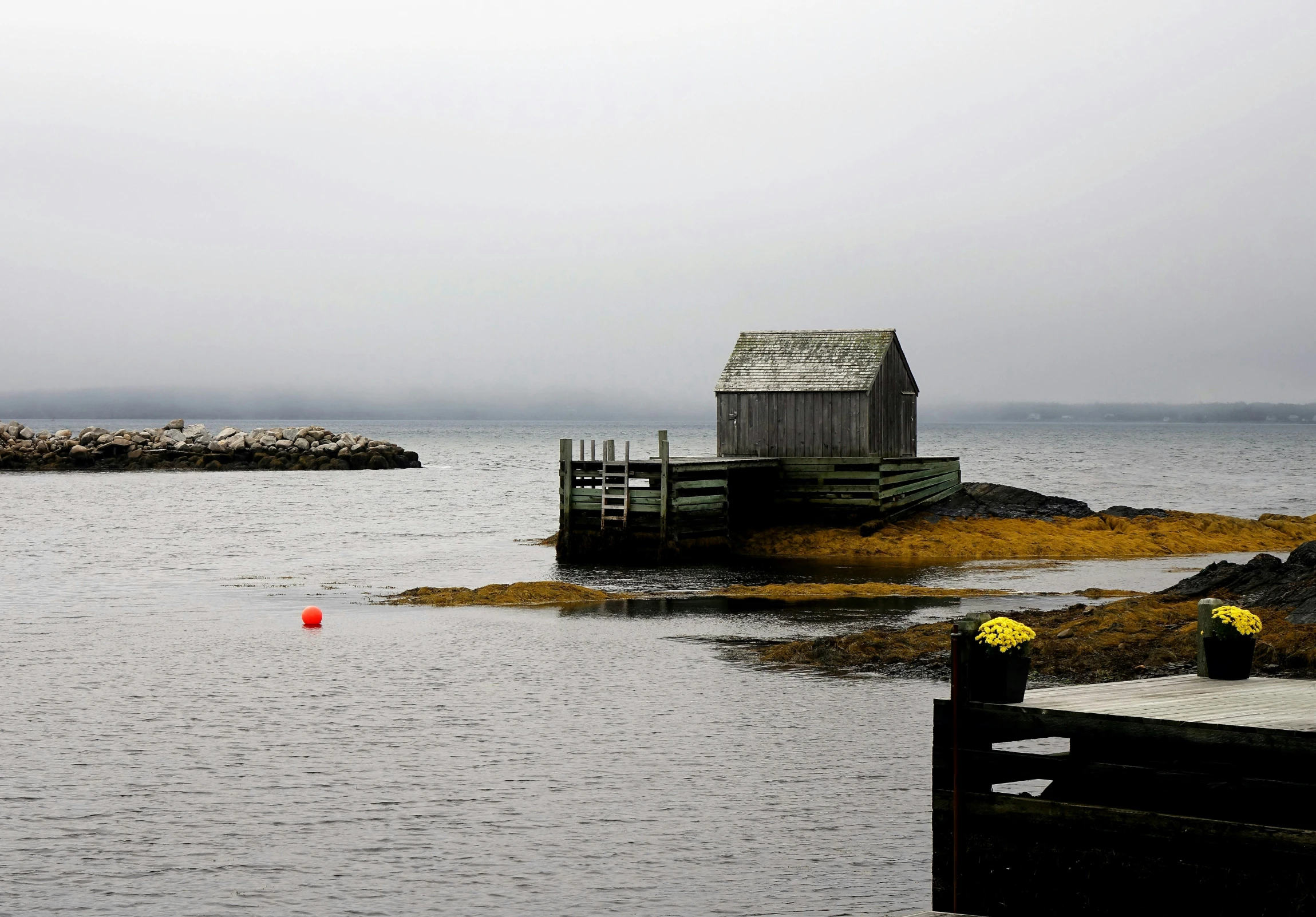 a boat sitting in the middle of the water next to small pier