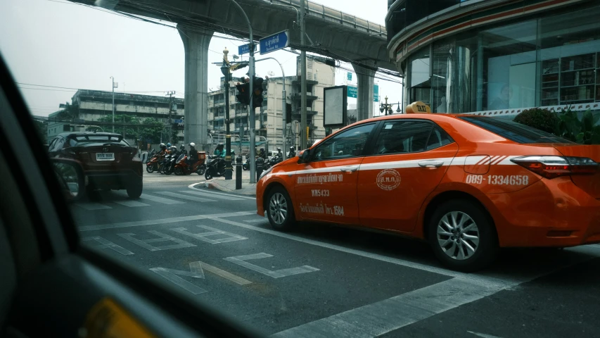 an orange car is traveling down the street