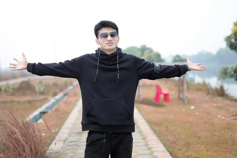 a young man in sunglasses is holding his arms out