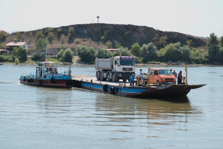 two trucks pulling a trailer down the river