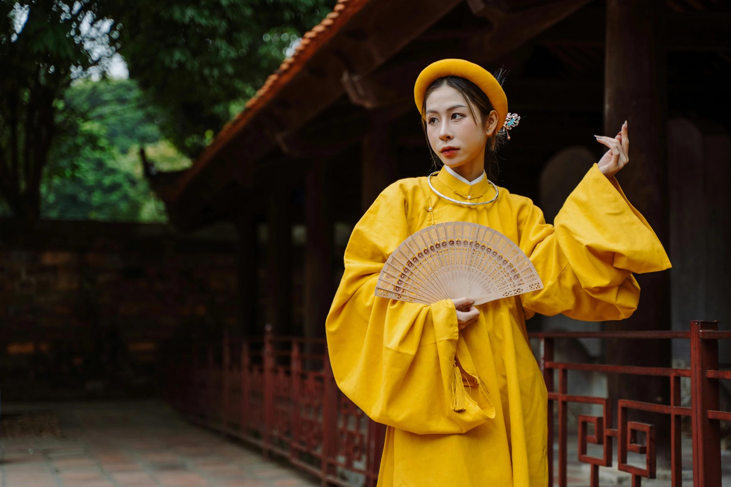 the woman wearing the traditional dress is holding an oriental fan