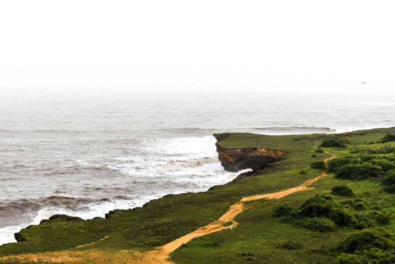 an image of the ocean with green grass on a hill