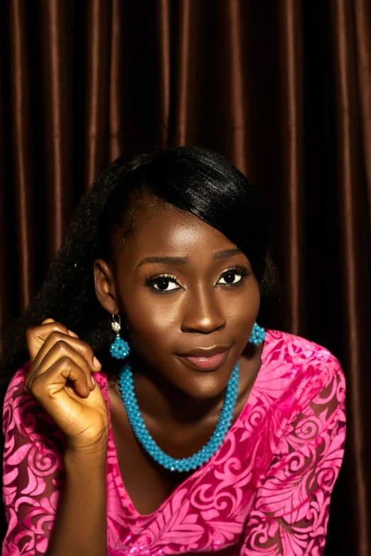 woman with blue beaded necklace and pink shirt posing