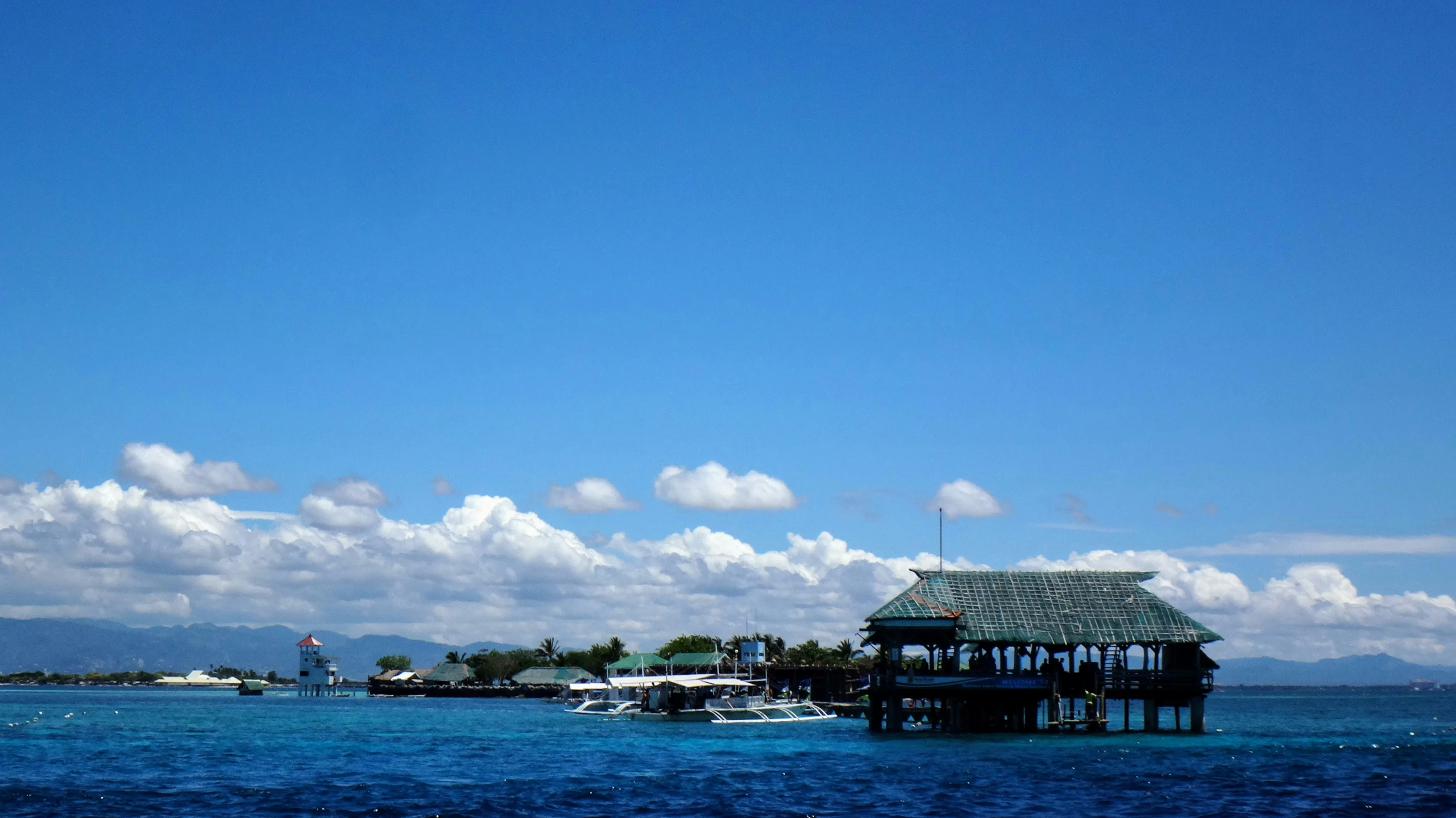 a group of buildings on water with white clouds in the background