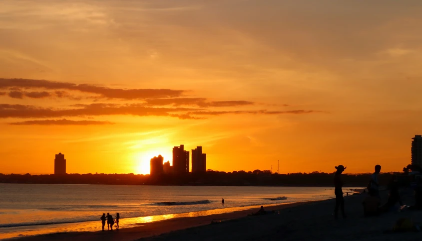 people walking on the beach and a city in the distance