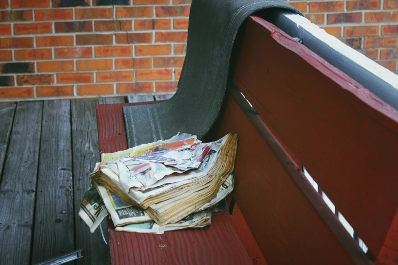 a stack of newspaper sitting on top of a wooden bench