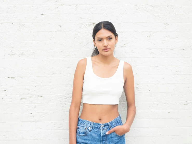 a beautiful young woman standing next to a white wall