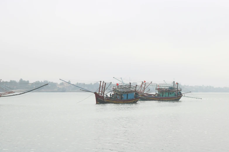 two ships on calm water under a gray sky