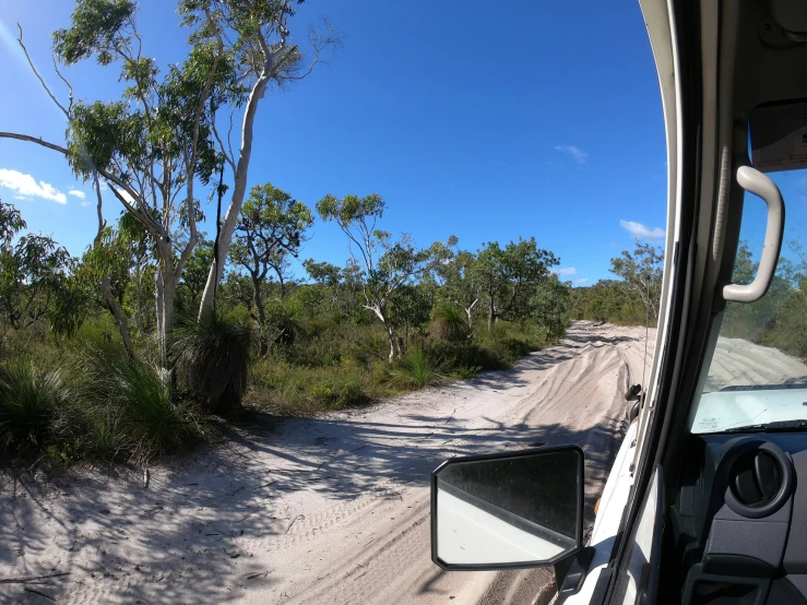 a vehicle is parked on a dirt road near the shore