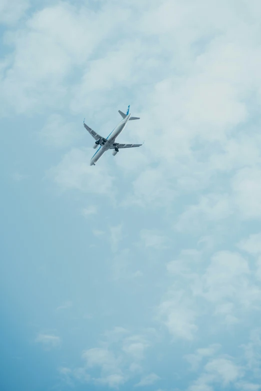 a plane is flying in the blue cloudy sky