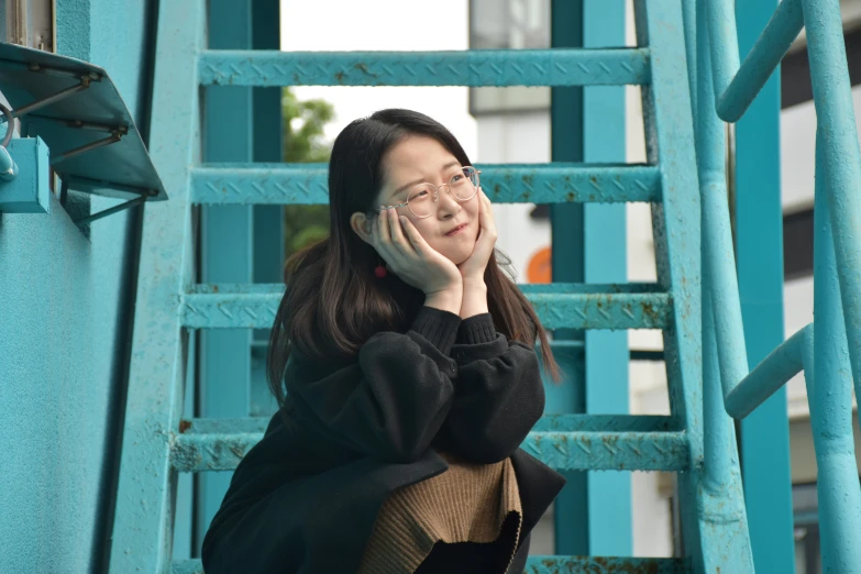 a girl is on a metal railing and talking on a cell phone