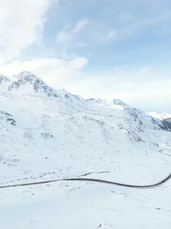 two people on skis riding uphill, with a hill in the background