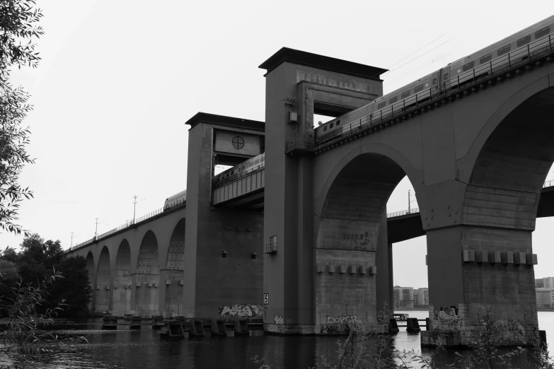 the river flows under two bridge arches in black and white