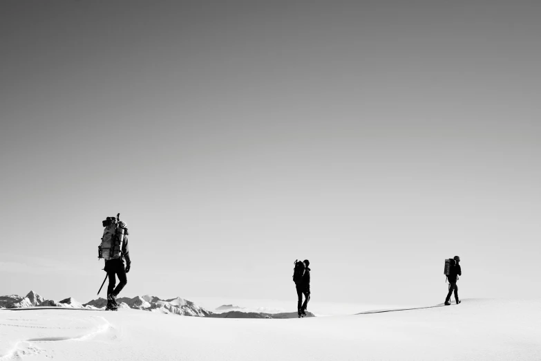 four people walking in the snow with one ski poles