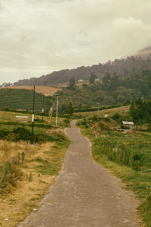 a picture of a dirt road with grass and hills in the background