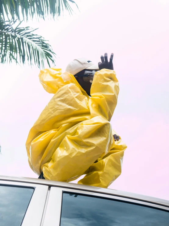 a man standing on the roof of a car while wearing a yellow suit and boots