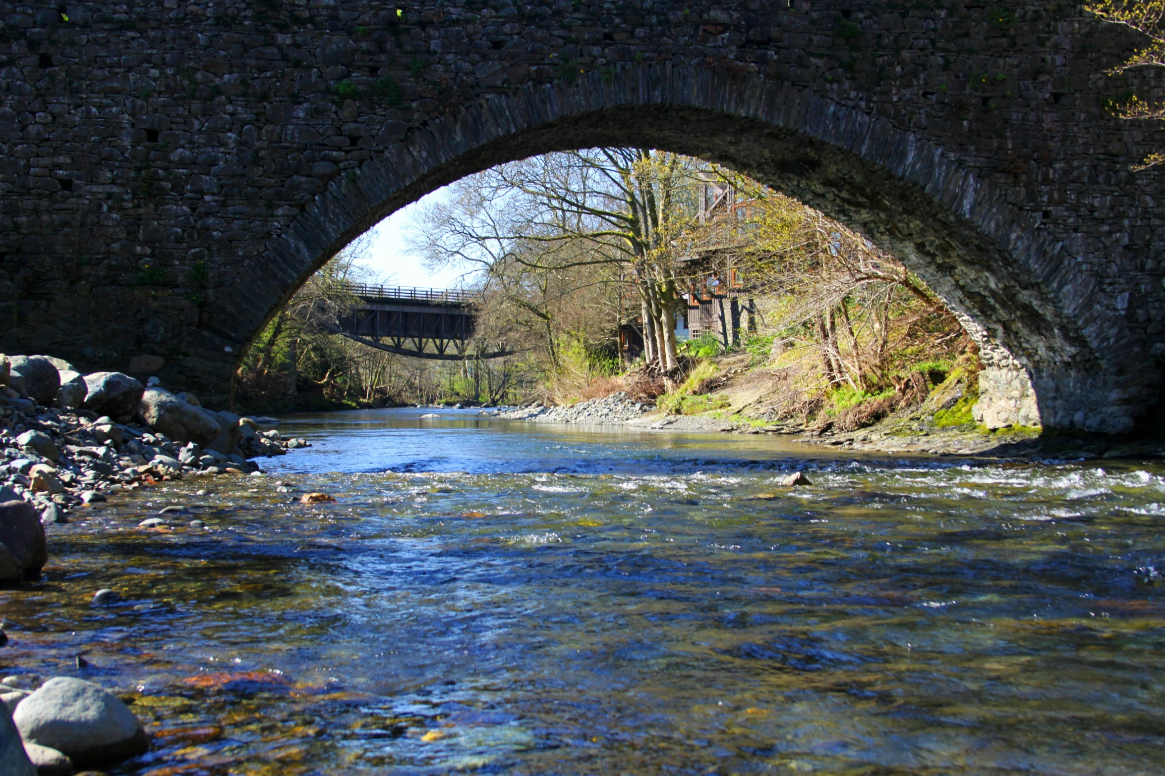 a river under a bridge with a wooden path