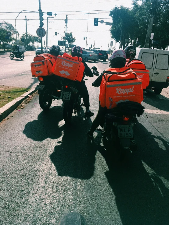 two motorcycles with orange bags in their backs on the street