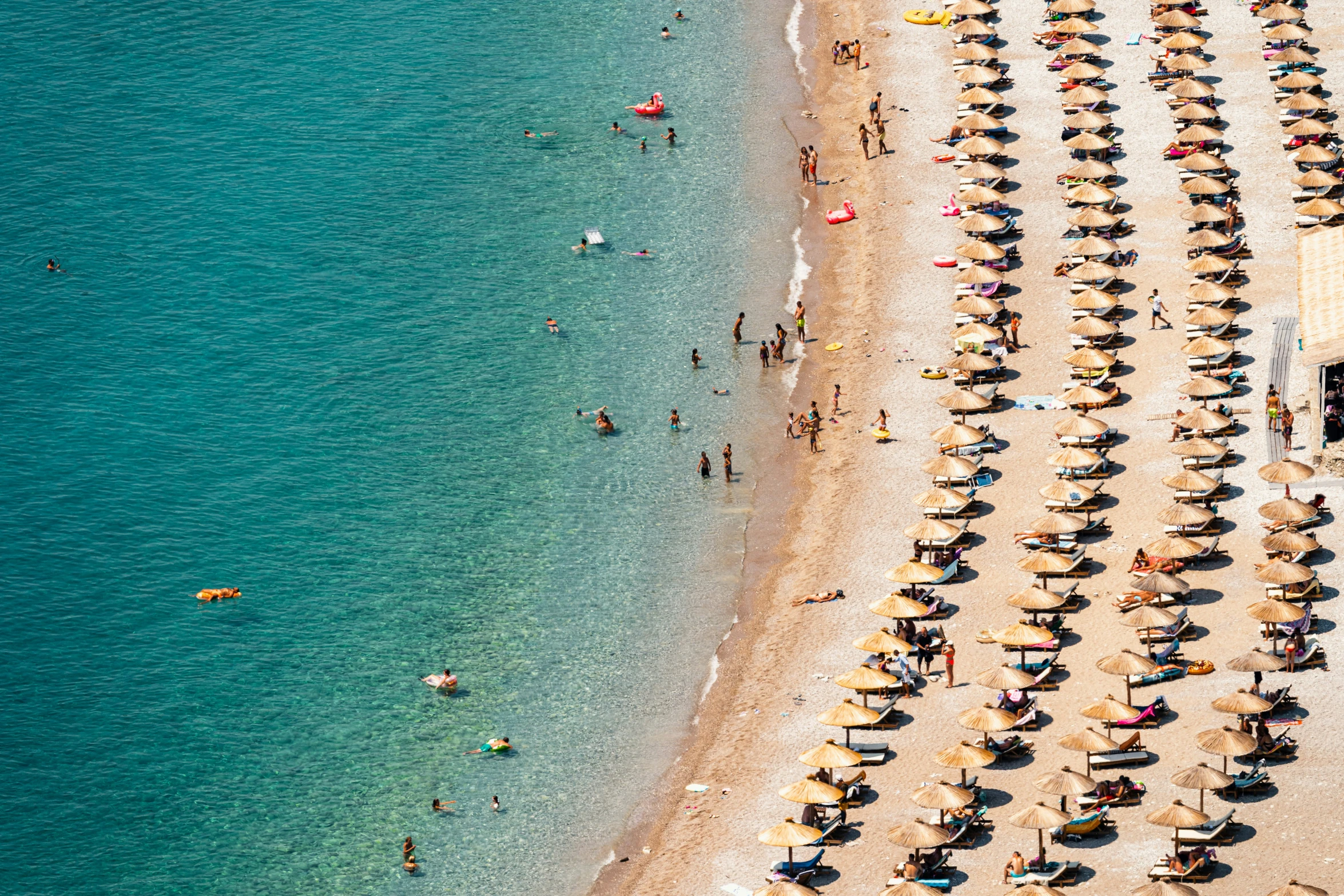 an aerial view of a beach with umbrellas and sun loungers