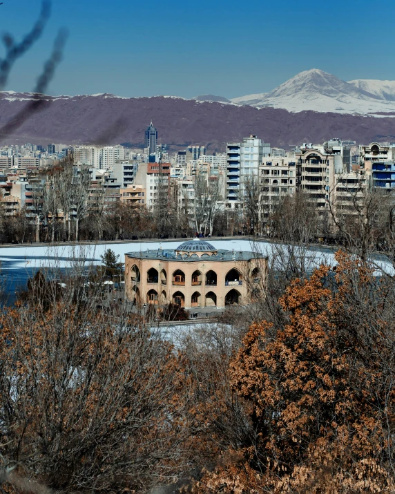 a building and mountains in the background, seen through a tree