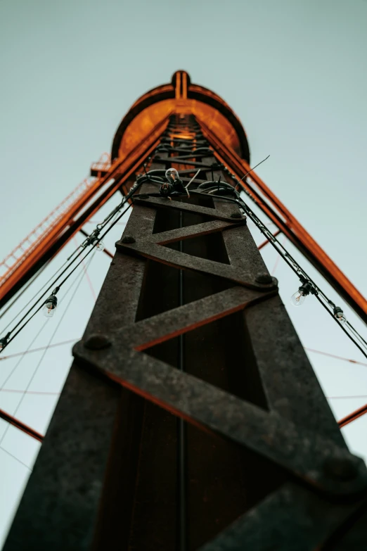 the top of a tall tower with metal and orange wires attached to it