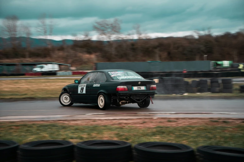 an automobile car drives along the course on a wet track