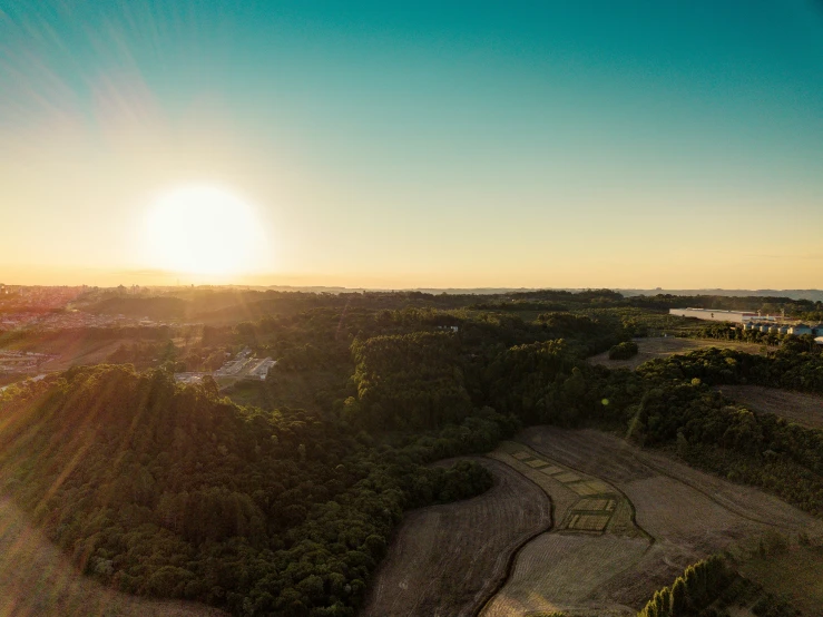 the sun shining over the trees and land