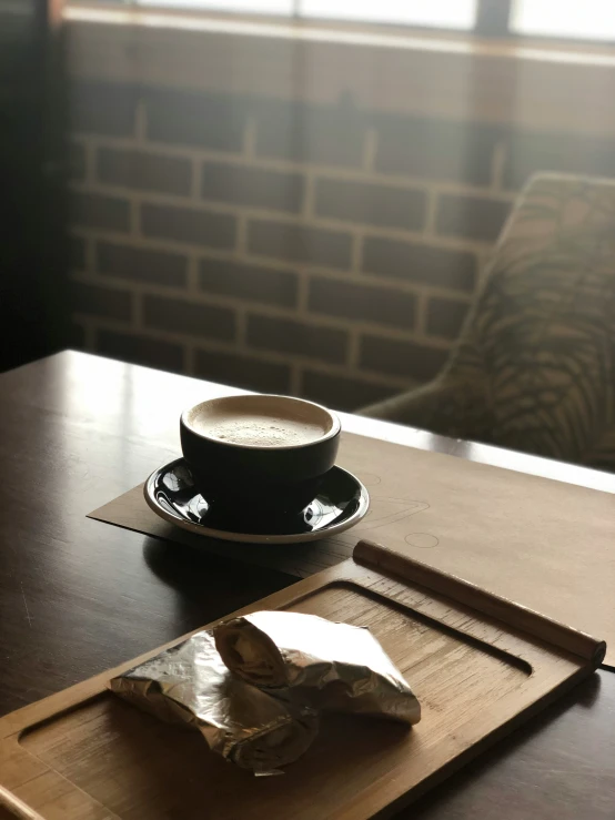 a cup of coffee sits on a wooden tray