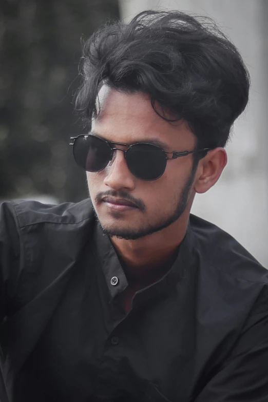 a young man wearing sunglasses looking back over his shoulder