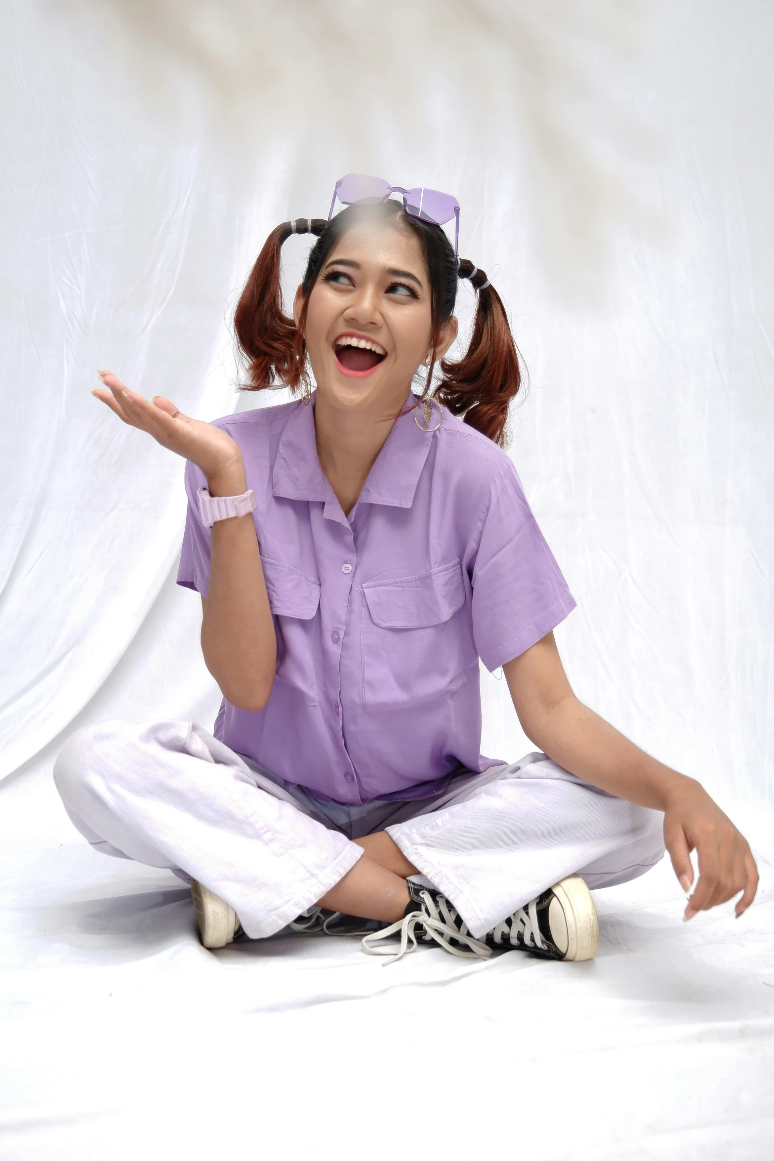 a woman with a pink shirt is sitting on the ground and she has her hands wide open