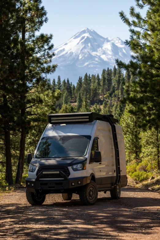 a van is on the side of a road with a mountain in the background