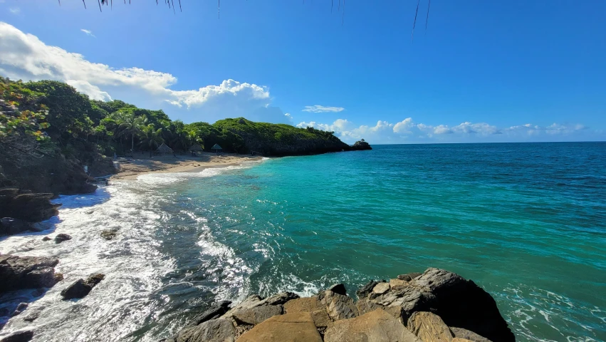 the shoreline has rocks near it and some blue water