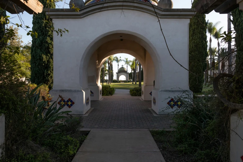 an archway in a garden with a clock tower on top