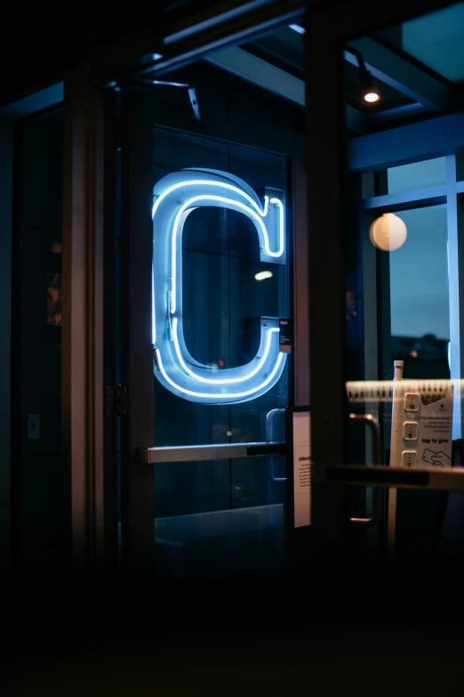 the letter c lit up against a door with the neon sign