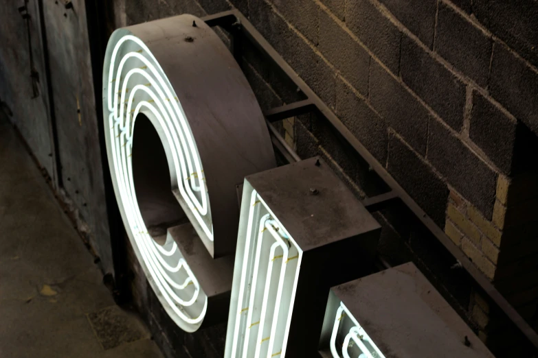 three light up letters on display with bricks behind them