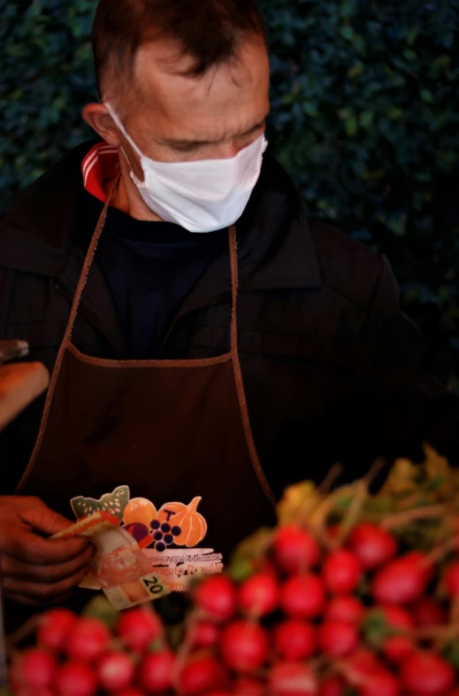 a man wearing a face mask standing at an outdoor market