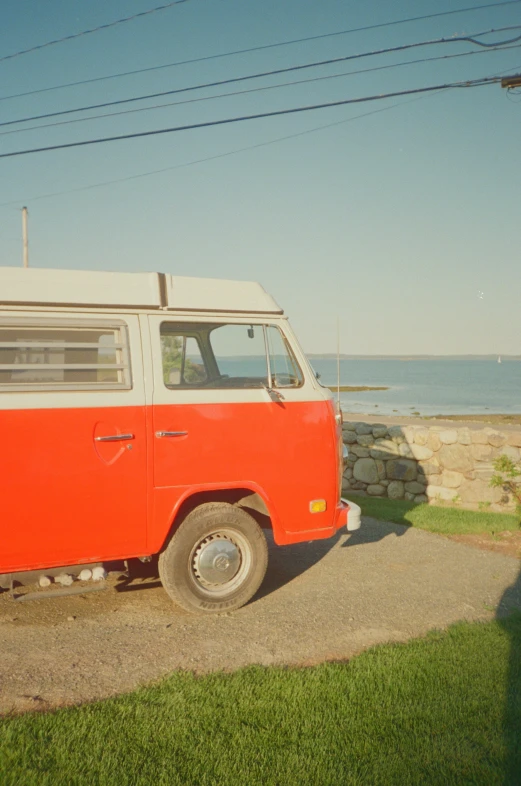 an orange and white van is parked by the water