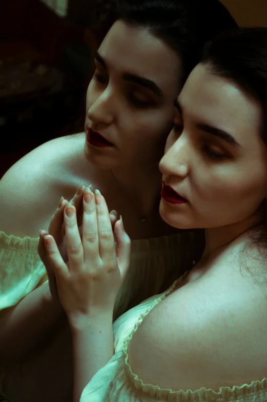 two woman sit close together to one another in bed