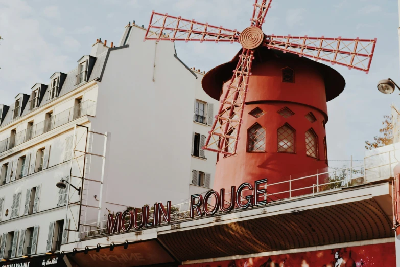 a red windmill on top of a building next to white buildings