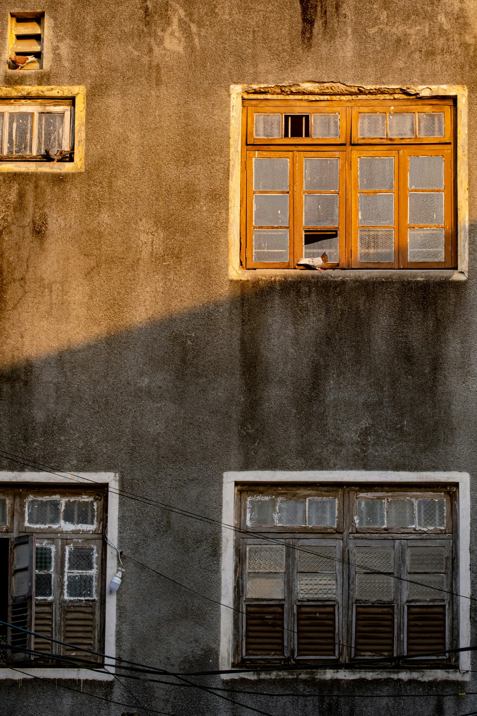 an old building with four open windows and a chair on the window