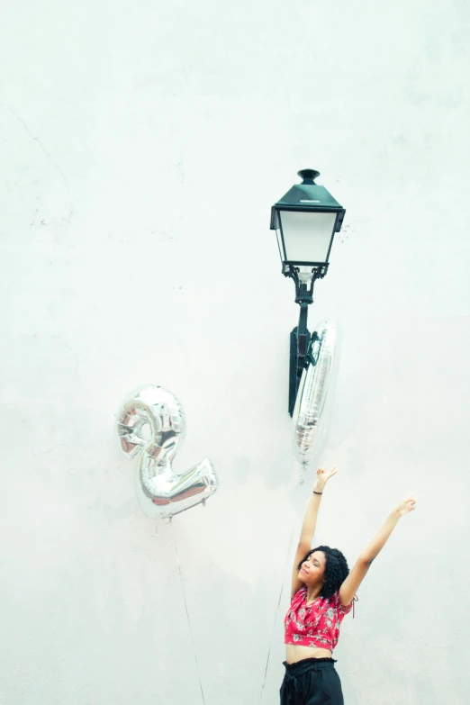 woman standing next to a lamp post and hanging balloons