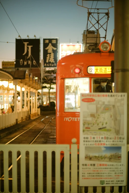 a train traveling past a tall white fence