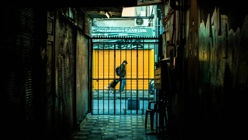 a person walking down an alley way in front of gate