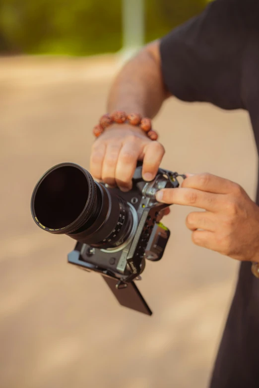 the hands are holding a camera near a body of water