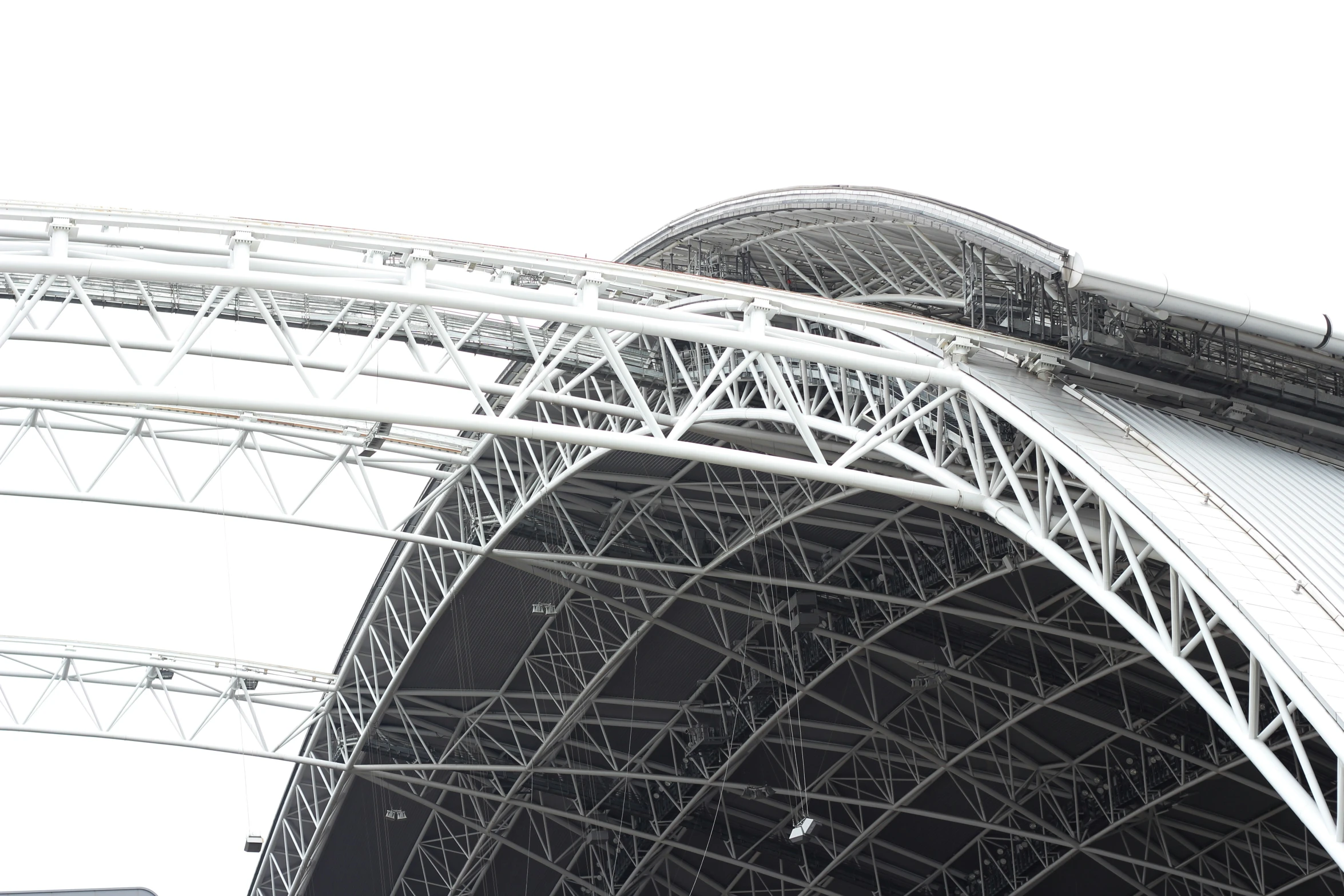 a silver, curved stadium stands on top of a cloudy sky