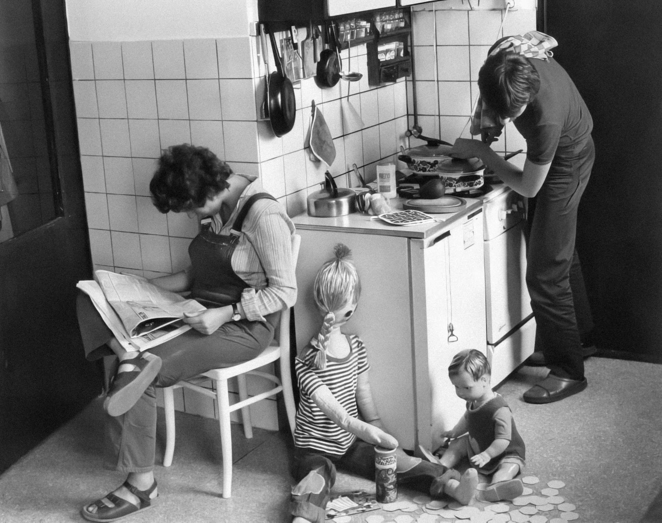 a woman and two children cooking in the kitchen