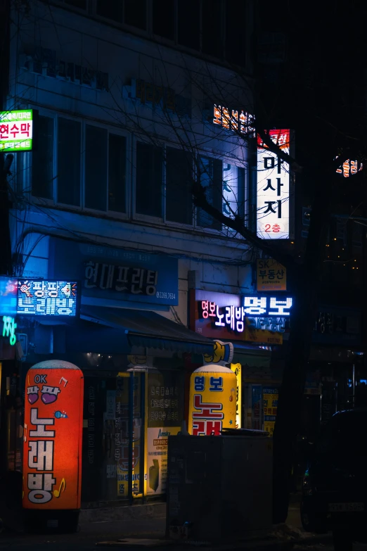 an asian street at night with neon signs lit up